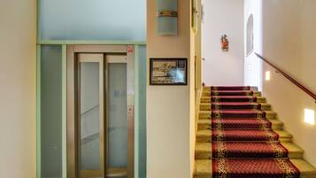 A staircase with red carpeted steps leading to an elevator.