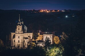 A historic church with a prominent dome and bell tower, surrounded by trees and set against a night sky.