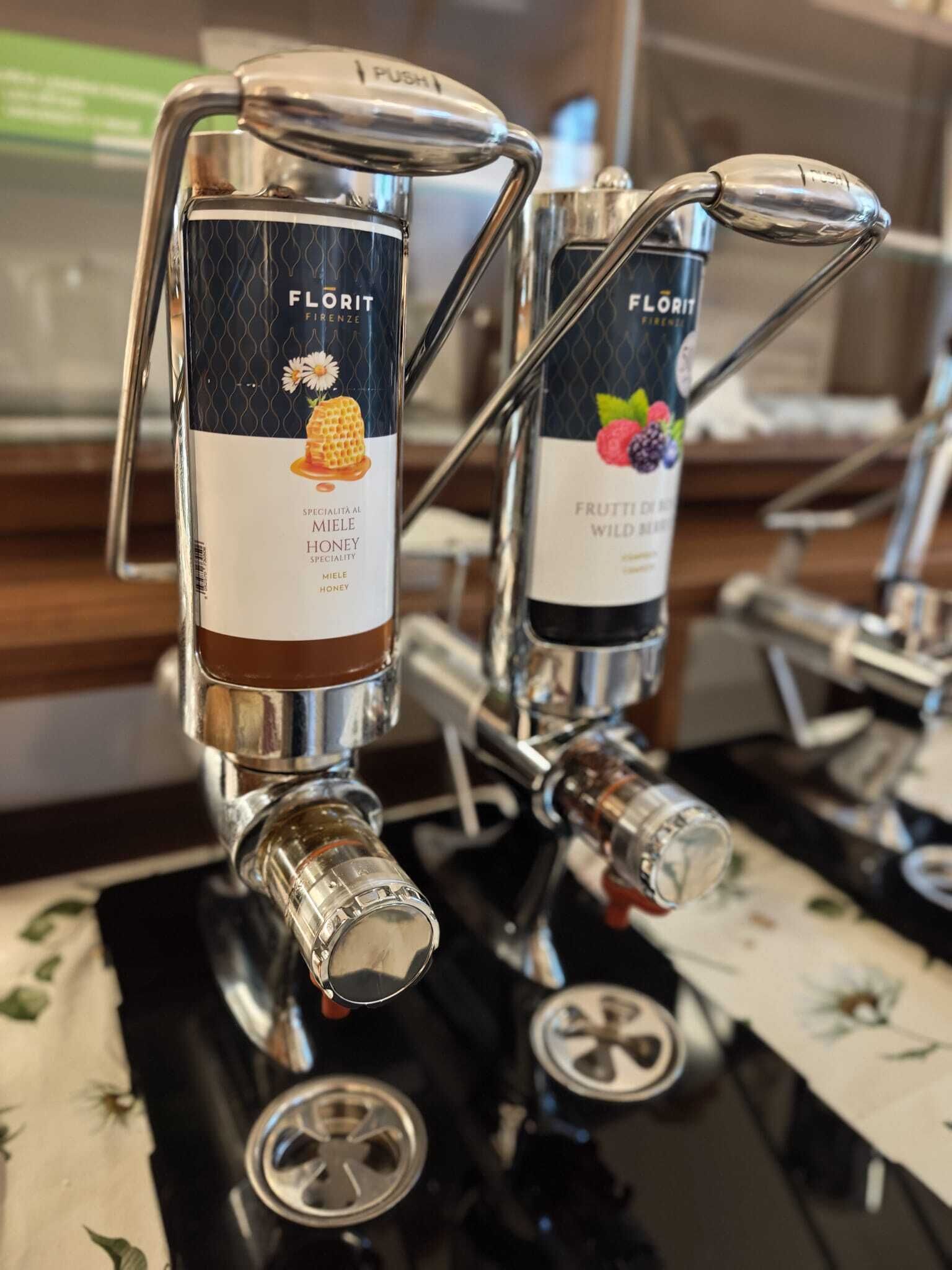 Dos grifos de cerveza Florit con sabores a miel y frutos silvestres, colocados sobre una encimera con mantel floral.