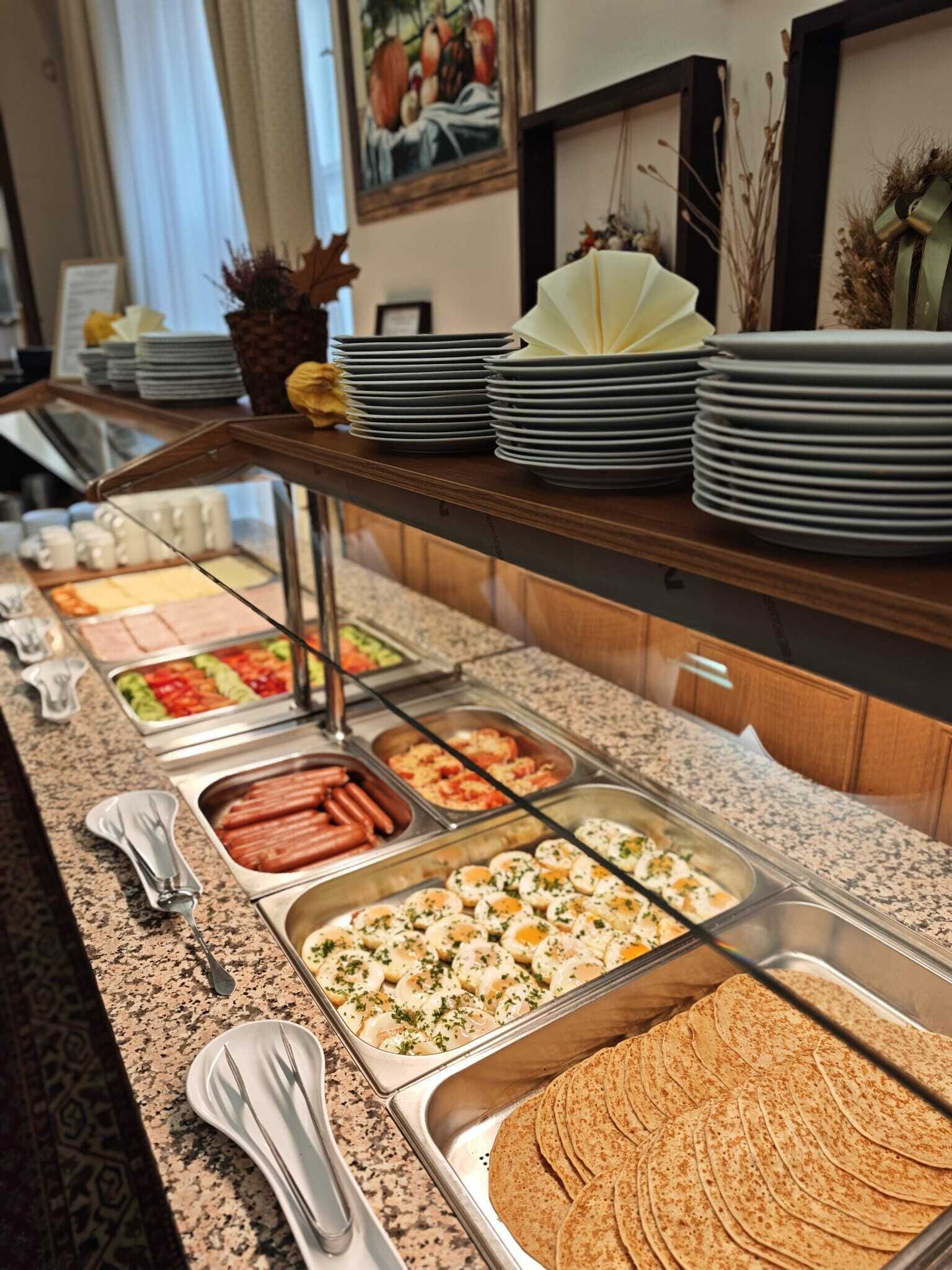 Un bufé con diferentes opciones de comida, como salchichas, huevos y tortillas.