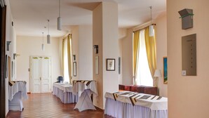 Passadís d'hotel amb diverses taules preparades per dinar, una porta al final i una balança penjada a la paret.