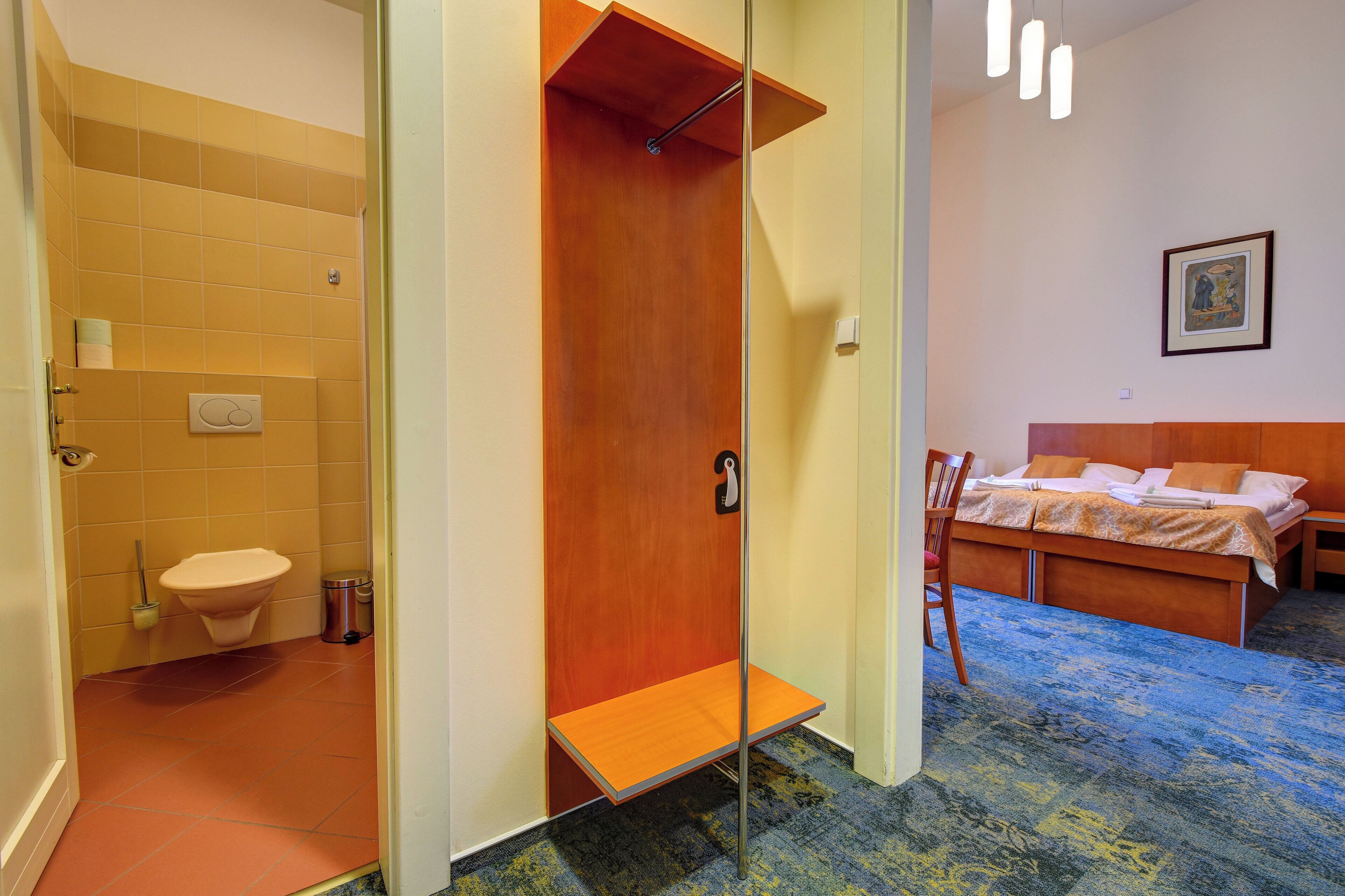 A hotel room with a wooden bed, a bathroom with a toilet and sink, and a shower area.
