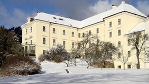Un edifici gran de diverses plantes amb una façana simètrica, nombroses finestres i un teulat cobert de neu.