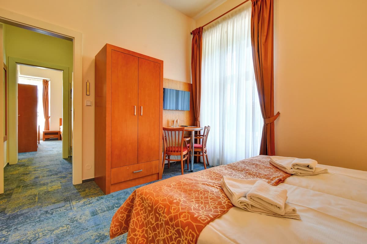 A hotel room with a bed, a desk, and a wardrobe.