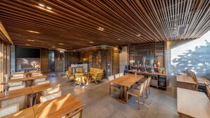 A modern interior with wooden ceiling panels, a central seating area with tables and chairs, and a bar area with shelves and decorative items. - Bonny Boutique Hotel Da Nang (Da Nang)