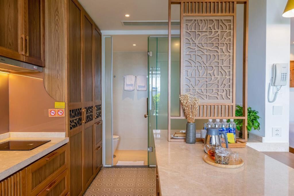 A modern kitchen with wooden cabinets, a glass shower enclosure, and a decorative partition with the word "HYDRUS" on it.