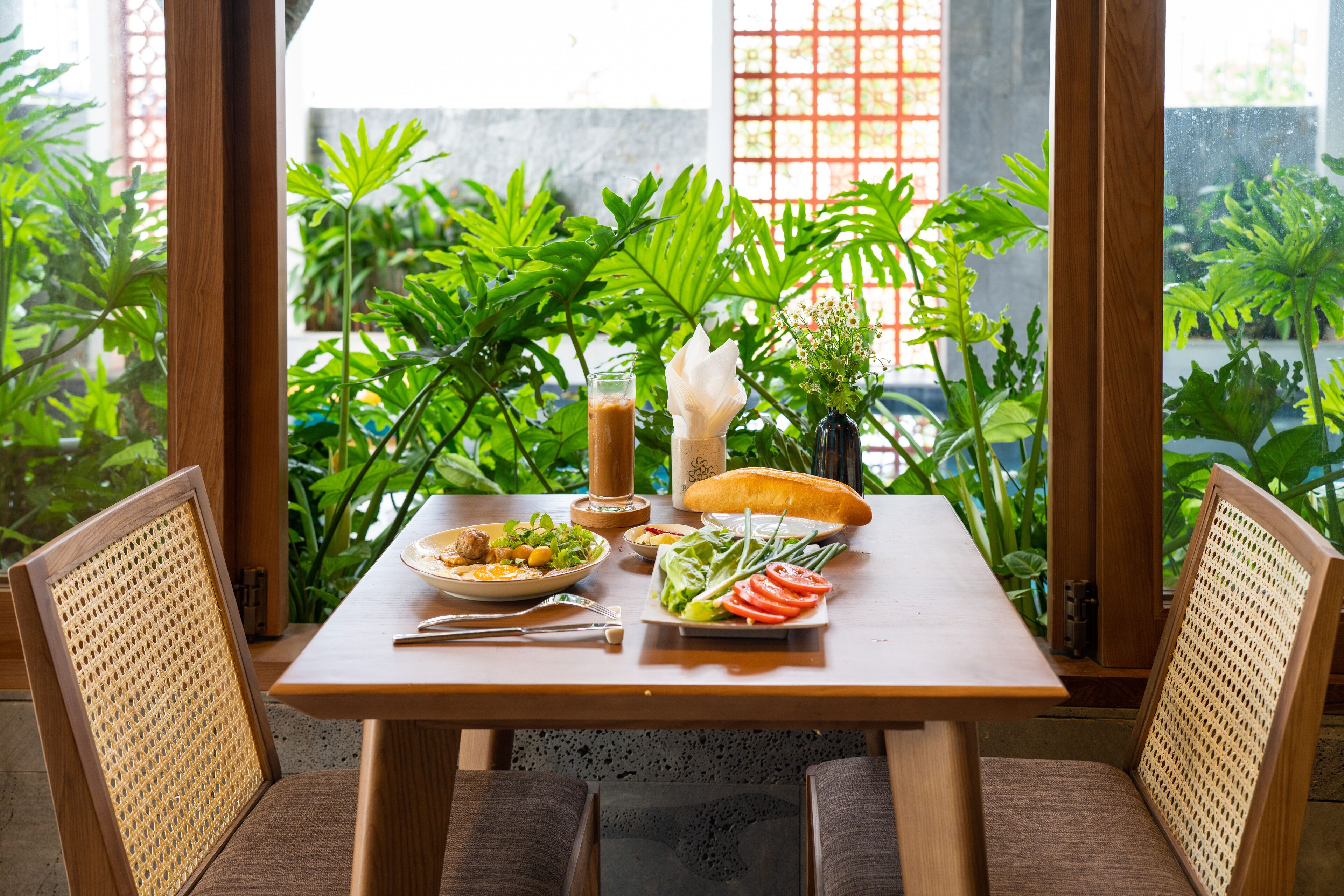 Een eettafel met een maaltijd, omringd door stoelen en planten.