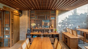 A wooden dining area with a long table and chairs, surrounded by shelves with various items and decorative pieces. - Bonny Boutique Hotel Da Nang (Da Nang)