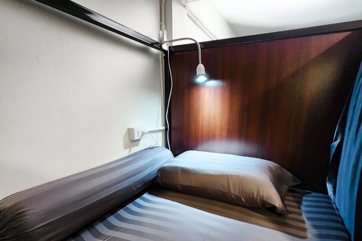 A compact, well-lit room with a bunk bed, a small desk, and a window providing natural light.