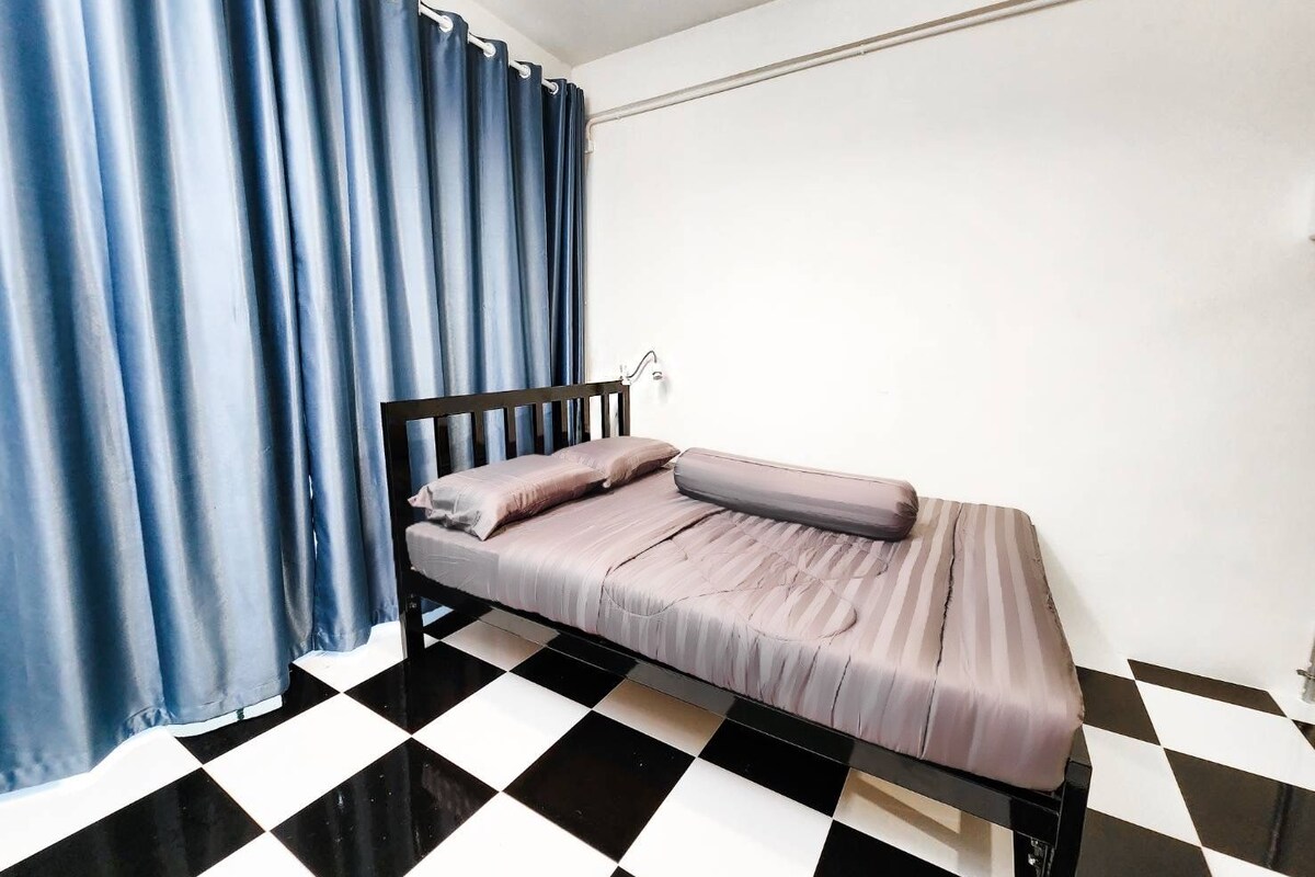 A room with a bed, a checkered floor, and blue curtains.