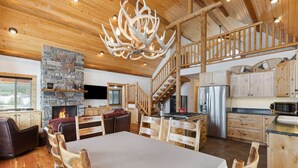 A spacious wooden interior with a dining area, kitchen, and fireplace.