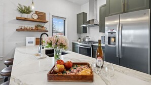 Cozinha moderna com bancada de mármore, eletrodomésticos de aço inoxidável e adega embutida.