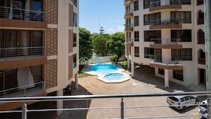 Un immeuble résidentiel à plusieurs étages, doté de balcons et d’une piscine.