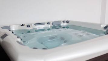 A rectangular hot tub with multiple jets, a control panel, and a glass interior.