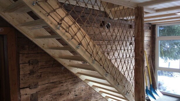 A wooden staircase with a rope safety net, a fire extinguisher, and a window with a view of trees. - Ferienhof Wäldle 2 Balderschwang - Direkt an der Loipe mit Motorradvermietung (Balderschwang)