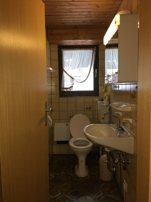 A compact bathroom with a toilet, sink, and window.