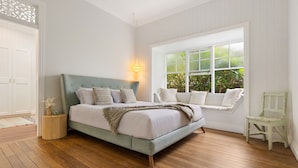 A bedroom with a bed, a window seat, and a chair.