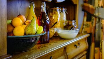A wooden cabinet with a bowl of fruit, a bottle, and a jar.