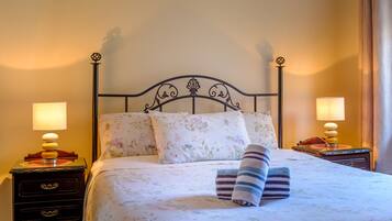 A neatly made bed with floral bedding, two bedside lamps, and a striped towel.