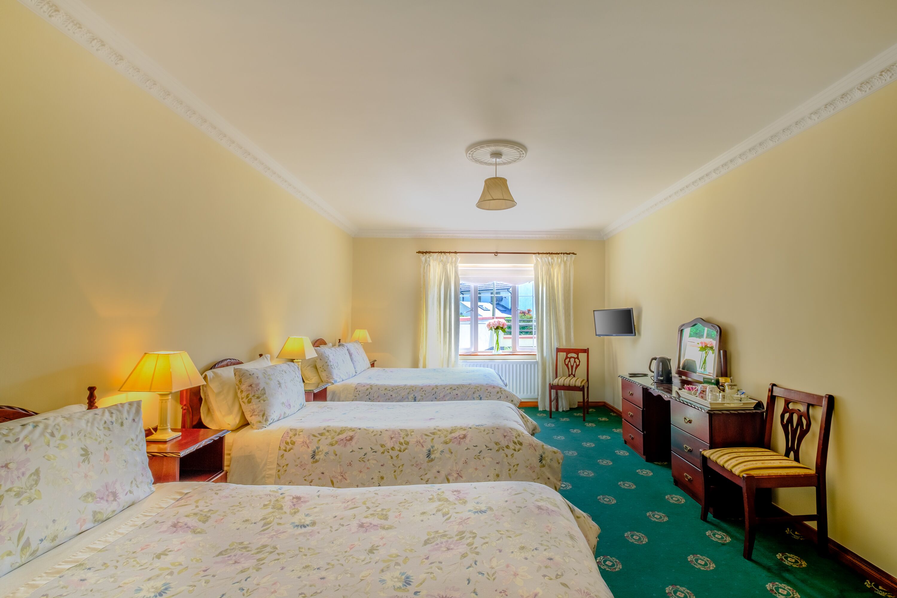 Een hotelkamer met twee bedden, een bureau, een stoel, een televisie en een raam met gordijnen.