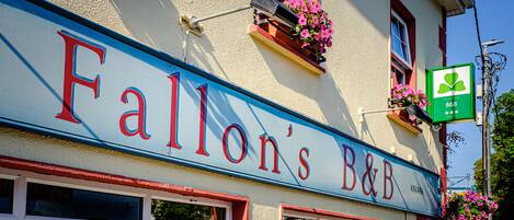 A building with a sign reading "Fallon's B&B" and a green sign with a clover logo.