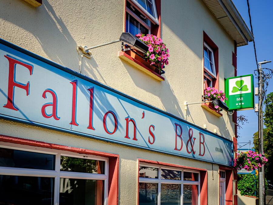 Un edificio con un letrero que dice "Fallon's B&B" y un cartel verde con un logotipo de trébol.