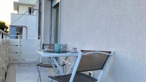 A balcony with a white table and two chairs, a window, and a view of neighboring buildings. - Casa Brina By Home080 (Monopoli)