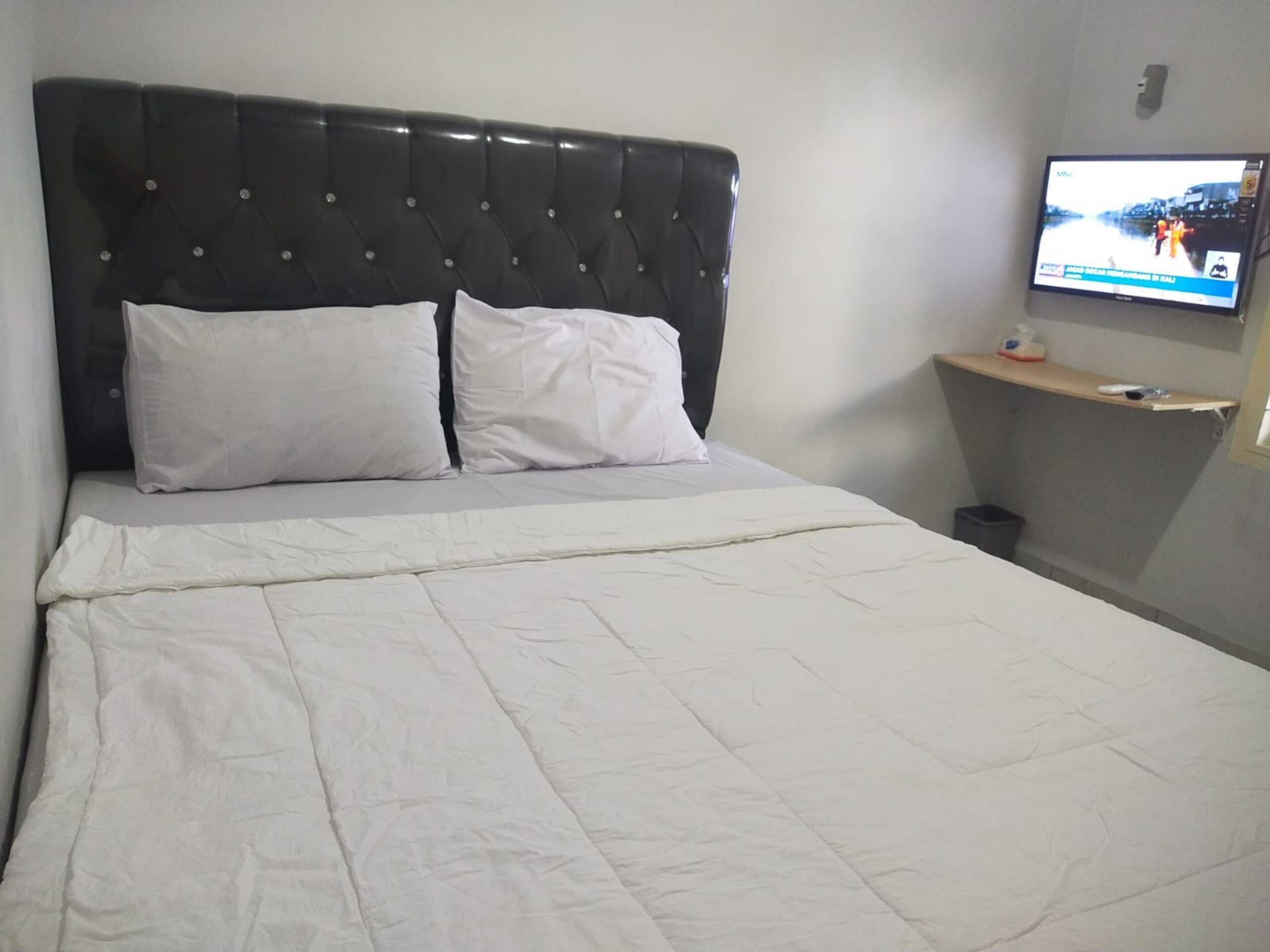 A neatly made bed with white bedding and a tufted headboard.
