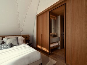 A bedroom with a bed, bedside table, and a wooden wardrobe with a mirror.