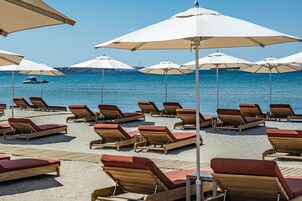 En la playa, sillas reclinables de playa, sombrillas, toallas de playa