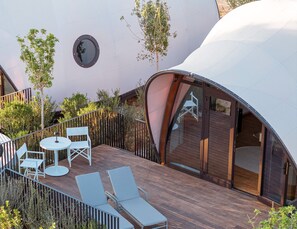 A modern outdoor deck with a wooden floor, white lounge chairs, and a small round table.