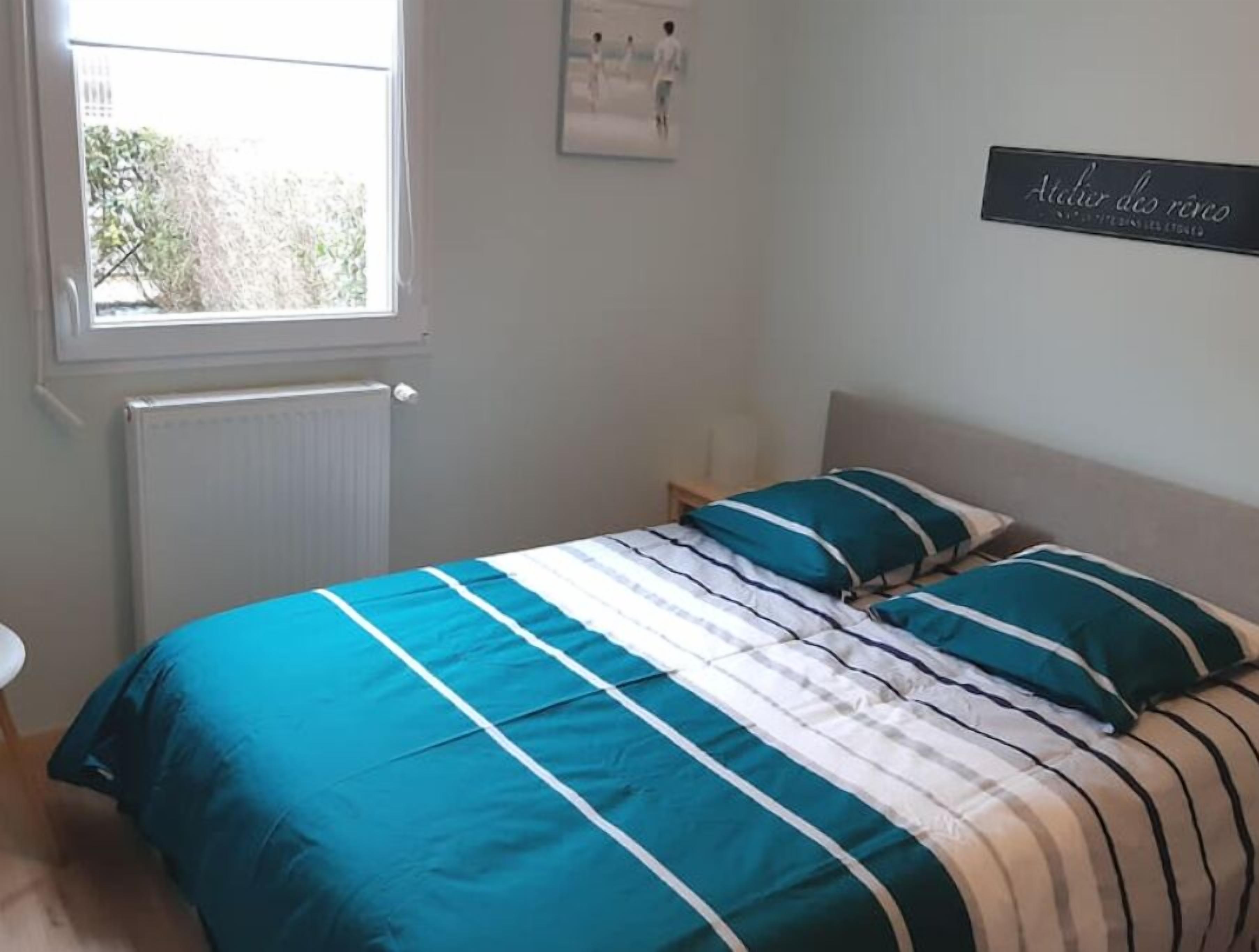 Een slaapkamer met een bed, een raam, een radiator en een bordje aan de muur.