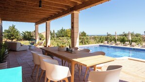 Un espace extérieur abrité comprenant une piscine, une table en bois et des chaises.