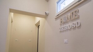 A hallway with a door labeled "1" and "2", a wall-mounted sign reading "HOME ZERO80", and a window above the sign. - Marco's House by Home080 (Monopoli -BA-)