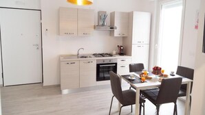 A modern kitchen with light wood cabinets, a gas stove, and a dining area with a table and chairs. - Marco's House by Home080 (Monopoli -BA-)