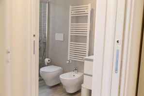 Une salle de bain équipée de toilettes, d’un bidet et d’un porte-serviettes.