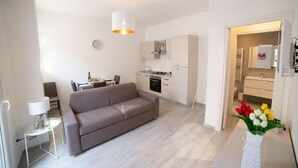 A modern living room with a sofa, a dining table, and a kitchen area. - Marco's House by Home080 (Monopoli -BA-)
