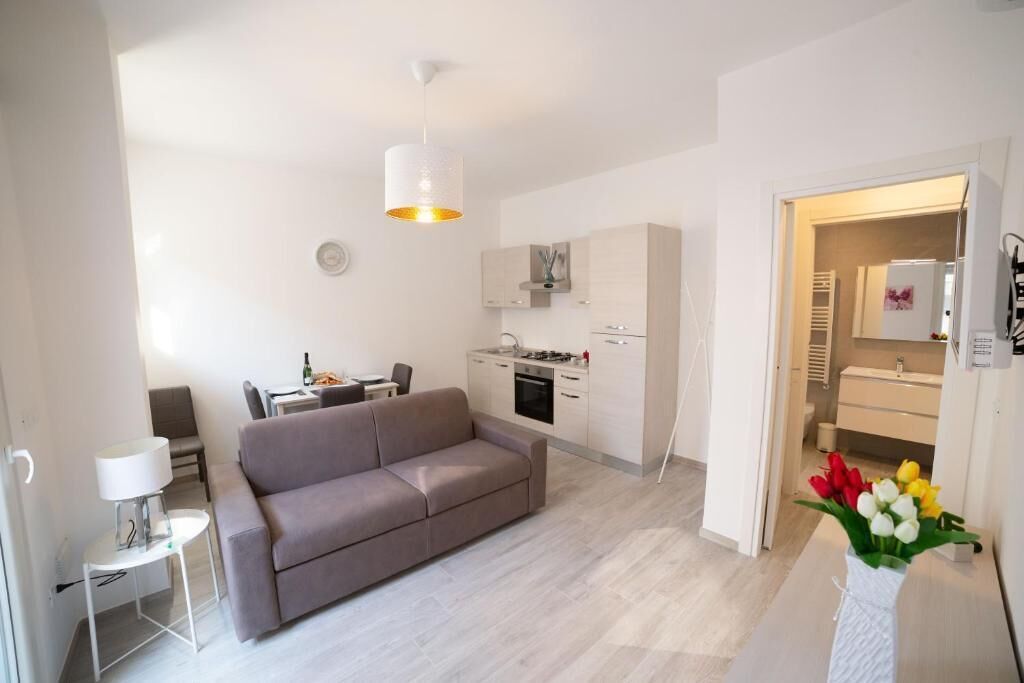 A modern living room with a sofa, a dining table, and a kitchen area.