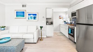 A modern kitchen with white cabinetry, a stainless steel refrigerator, and a coffee maker on the counter.