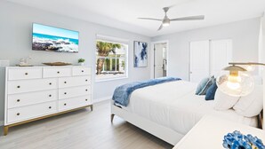 A bedroom with a bed, a dresser, a television, a ceiling fan, and a window with a view of palm trees. - Private Heated Pool - 100 Steps to Beach Access - 5-min walk to Siesta Key Village (Siesta Key)