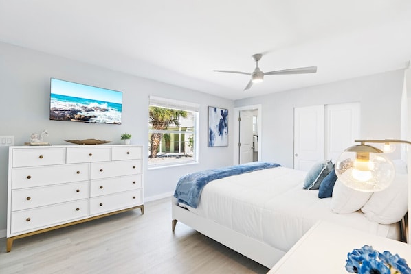 A bedroom with a bed, a dresser, a television, a ceiling fan, and a window with a view of palm trees. - Private Heated Pool, 100 Steps to Beach Access, 5-min walk to Siesta Key Village (Siesta Key)