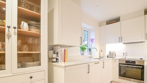 Une cuisine moderne avec des meubles blancs, un four en acier inoxydable et une fenêtre qui laisse entrer la lumière naturelle.