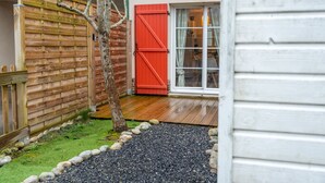 Una valla de madera, una puerta roja y una ventana con cortinas.