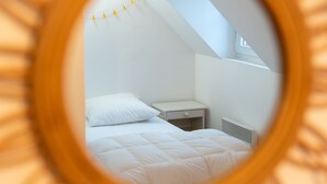 Un dormitorio con cama, mesita de noche y ventana.