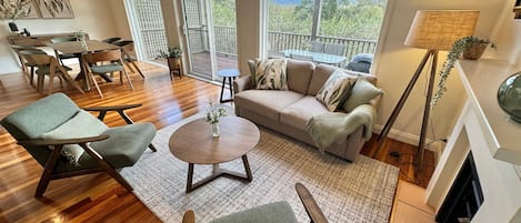 Un amplio salón con sofá, sillas, una mesa de centro y vistas al exterior.