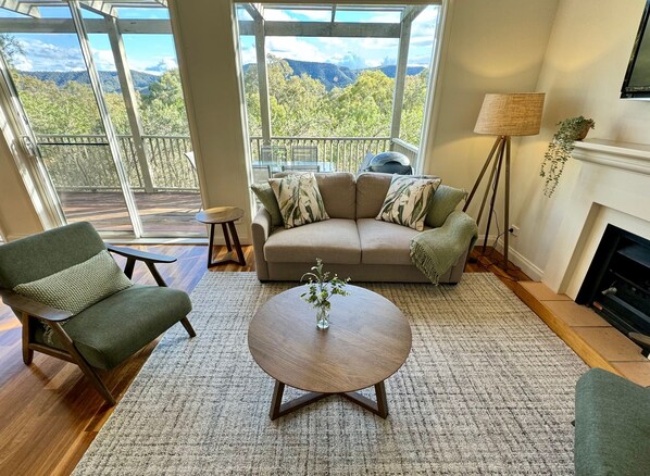 A living room with a sofa, armchair, coffee table, and a view of the outdoors.