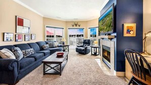 Ein Wohnzimmer mit einem dunkelblauen Sofa, einem Couchtisch, einem Kamin und einem großen Fernseher.