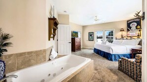 Ein Schlafzimmer mit einer großen Badewanne, einem Bett, einer Kommode und einem Fenster.