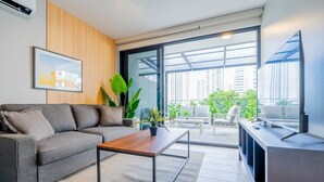 A modern living room with a grey sofa, a wooden coffee table, and a TV on a wooden stand.