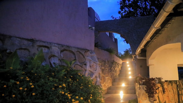 A stone staircase leading up to a building entrance, surrounded by greenery and illuminated by warm lights. - Fuego Hotel (Kampala)